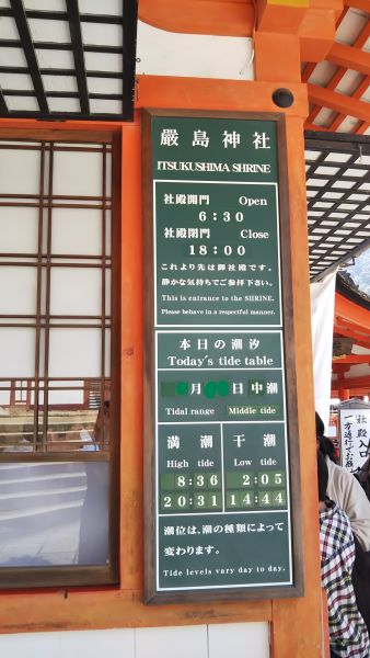 Tide schedule board showing high and low tide times at Itsukushima Shrine