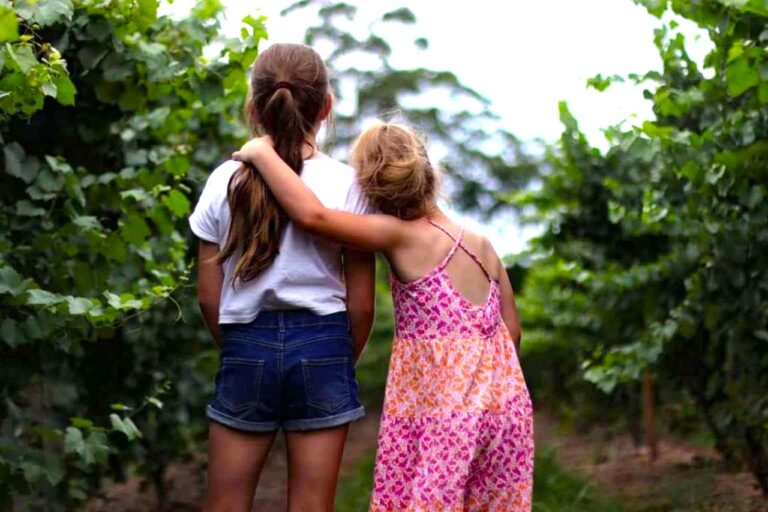 Two girls walking together with their arms around each other